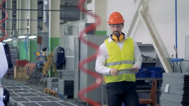 Fabriek werknemer komen en waardoor een robot te beginnen boren — Stockvideo