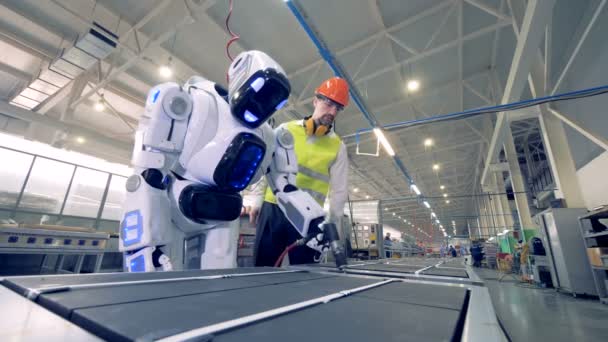 Lucrătorul din fabrică reglementează setările roboților prin telecomandă în timpul procesului de lucru — Videoclip de stoc
