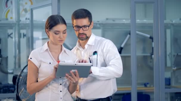 Male engineer is giving instructions to a female one holding a tablet computer — Stock Video