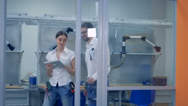 Ingenieros femeninos y masculinos están entrando juntos en una oficina, sonriendo y hablando — Vídeos de Stock