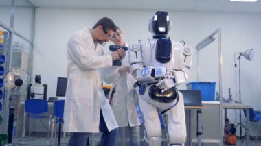 İki teknisyen bir matkapla bir insan benzeri robot ayarlamalar yapıyoruz