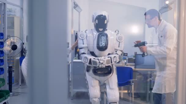 Människoliknande cyborg blir kontrollerat och fast av två ingenjörer — Stockvideo