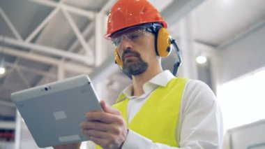 Bir erkek fabrika işçinin içinde muhafaza onun tablet ile çalışma üniforma yakın çekim