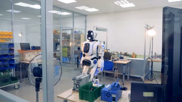 Sorridente cyborg sta muovendo la testa e il corpo in un laboratorio — Video Stock