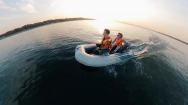 Two men are sailing in a dinghy along the coast