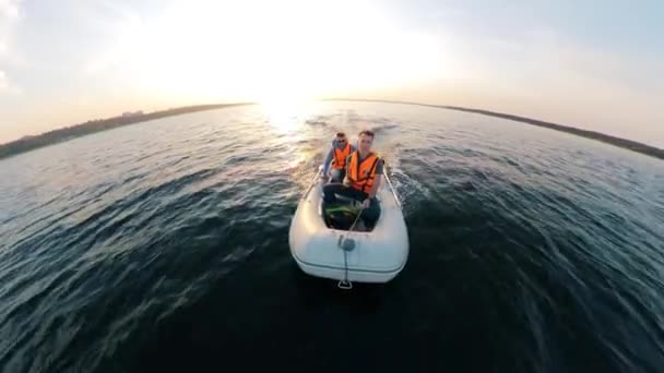 Vista frontal de dos hombres en chalecos salvavidas sentados en un bote en movimiento — Vídeos de Stock