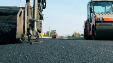 Man works on a road with machines, laying asphalt.