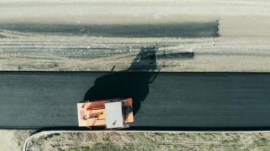 Big roller rides on a road with fresh ashpalt.