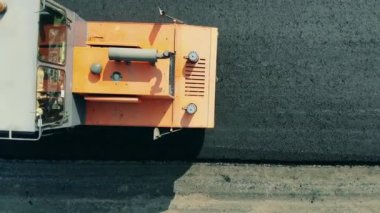 One machine rolls asphalt on a road.