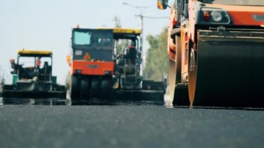 Road rollers work on a road during paving.