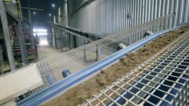 Kayalar ve kum bir fabrikada çalışan bir hat üzerinde hareket ediyor..