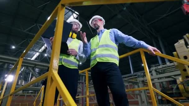 Werknemers staan in een fabriek interieur, controle apparatuur. — Stockvideo