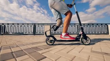 Ağır çekimde scooter süren engelli bir adamın yan görüntüsü