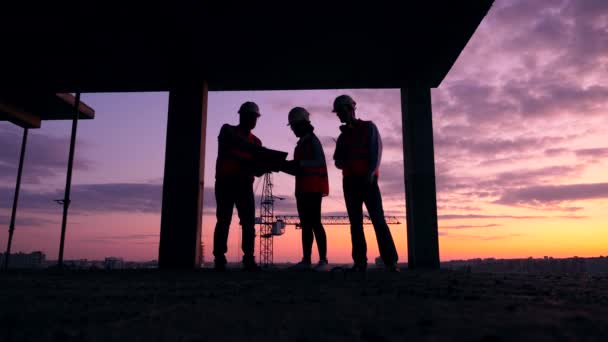 Ingenieurteam arbeitet auf dem Sonnenuntergang-Baugrundstück — Stockvideo