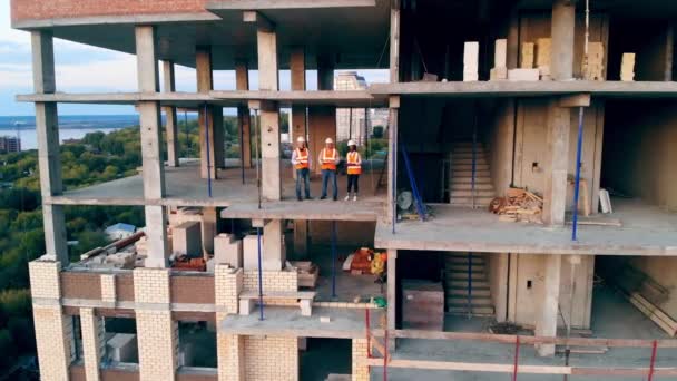 Equipo de ingenieros de pie en el sitio del proyecto de varios pisos — Vídeo de stock