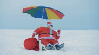 Karlı arazide Noel Baba telefonda konuşuyor.