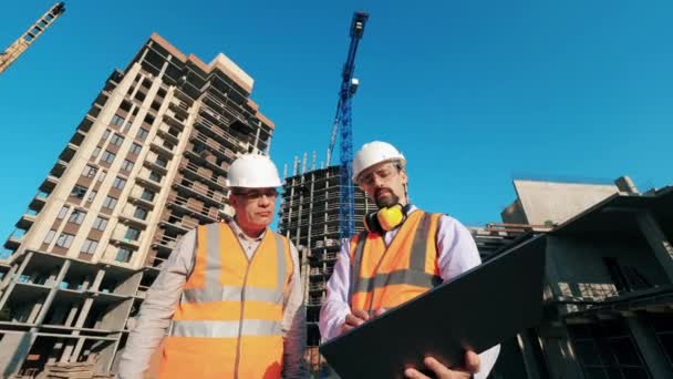 Lote de construção com dois arquitetos operando um computador — Vídeo de Stock