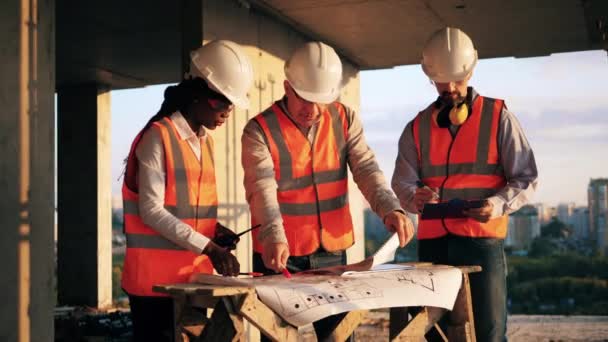 Equipe de trabalhadores da construção estão discutindo layouts — Vídeo de Stock