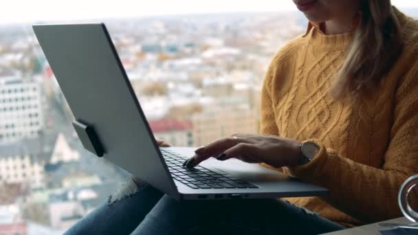 Una dama de negocios escribiendo en un ordenador portátil contra una vista de la ciudad — Vídeos de Stock
