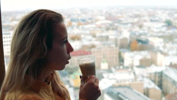 Stadsgezicht met een vrouw die koffie drinkt ernaast — Stockvideo