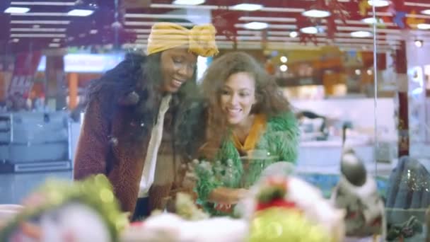 Las mujeres miran decoraciones mientras compran en un centro comercial . — Vídeos de Stock
