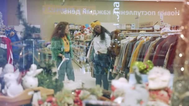 Amigos alegres revisan chaquetas coloridas en una tienda . — Vídeos de Stock