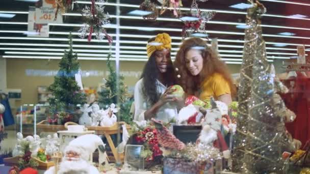 Fiatal nők ellenőrzik a karácsonyi ajándékokat egy boltban.. — Stock videók