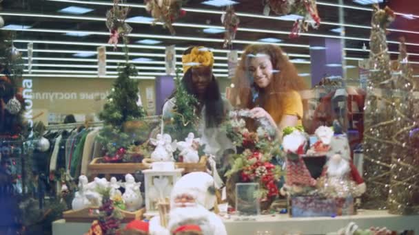 Два друга смотрят на праздничные украшения в торговом центре . — стоковое видео