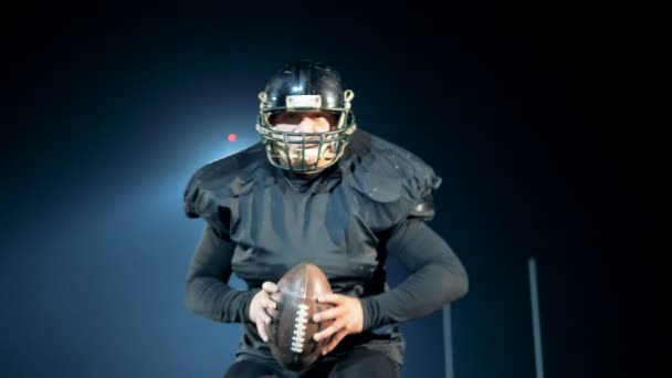 American football speler loopt op een veld met een bal, close-up. — Stockvideo