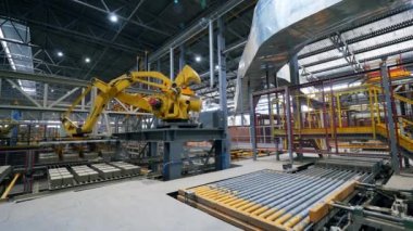 Otomatik makine modern bir fabrikadaki bir taşıyıcıya tuğla koyuyor..