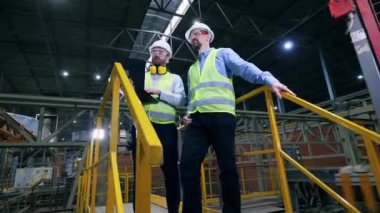 Mühendisler bir fabrikada durarak iş konuşuyorlar. Fabrikadaki profesyonel fabrika işçileri.