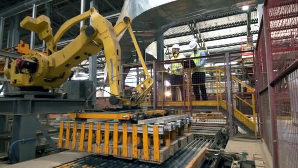 Los ingenieros revisan una máquina de trabajo en una fábrica de ladrillos. Ingenieros masculinos de fábrica en una fábrica moderna . — Vídeos de Stock