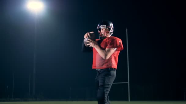 American football speler houdt een bal tijdens het lopen op een veld, close-up. — Stockvideo