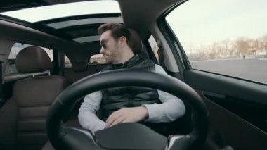 Self-driving autonomous car is parking by itself. A man is smiling while his car is moving automatically