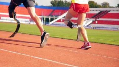 Protez bacaklı iki sporcunun ağır çekimde koşması.