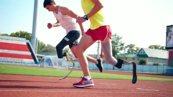 Movimento lento di due uomini con gambe bioniche che fanno jogging allo stadio — Video Stock