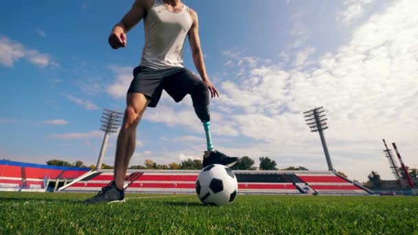 Futbol sahası ve top oynayan protez bacaklı bir adam. — Stok video