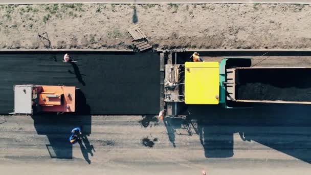 İşçiler ve endüstriyel makineler tarafından tutulan asfaltın yerleştirilmesi — Stok video