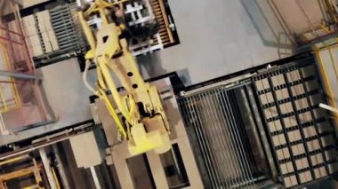 Taşıyıcıdaki tuğlaların yerini değiştiren robotik kolun üst görünümü
