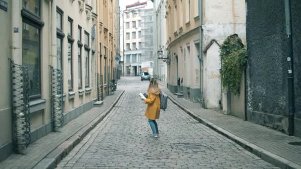 Женщина-туристка идет по узкой улице с картой — стоковое видео