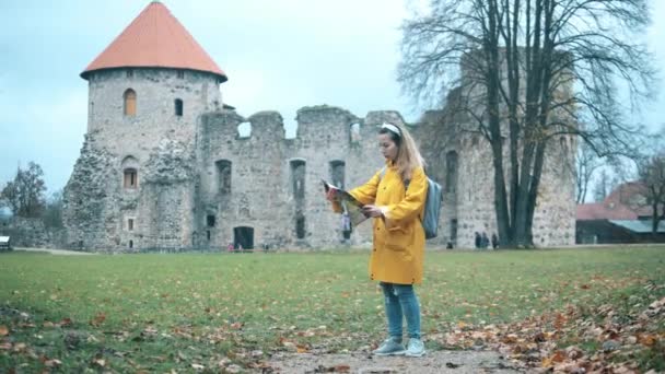 Egy nő egy térképpel az ősi vár mellett áll. — Stock videók