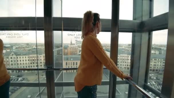 Hermosa mujer está bajando en un ascensor transparente — Vídeo de stock