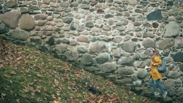 Женщина с картой идет по лестнице по древней стене — стоковое видео