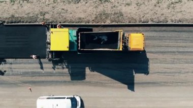 İşçiler yola asfalt saçıyor. Yol inşaatında çalışan inşaat işçileri..