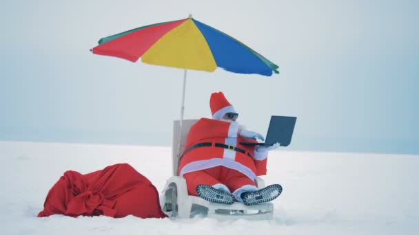 Claus working with a laptop, sitting on a deck chair, close up. — Stock Video