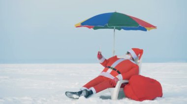 Noel Baba güverte sandalyesinde otururken tablete bakıyor, kapat..