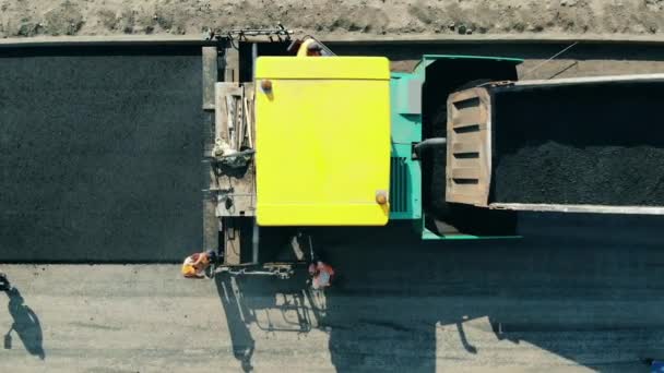 Machine de pavage d'asphalte sur un chantier de construction de route. Vue du dessus des camions remplis de bitum et des travailleurs autour d'eux — Video