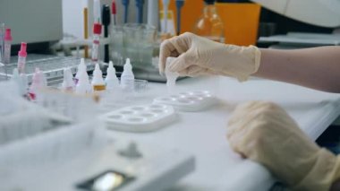 Kadın araştırmacı paletlere kimyasal damlatıyor.