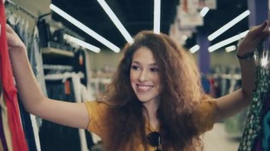Genç bayan elbiselerine bakıyor ve gülümsüyor.