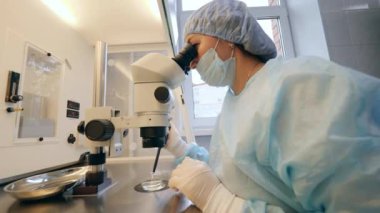 Kadın araştırmacı mikroskop altında kimyasalları analiz ediyor.